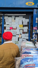 April 2023: people looking at classifieds ads in a busy street in Southall, London, UK